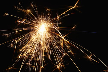 Christmas and New Year's illumination. Burning sparklers scatter bright exploding strips of sparks on a dark background.