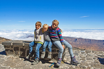 happy children sitting on a bench for one night at Altavista mountain camp site near Teide volcano, on the island of Tenerife, natural background, Spain