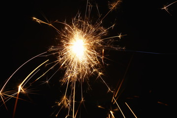 Christmas and New Year's illumination. Burning sparklers scatter bright exploding strips of sparks...