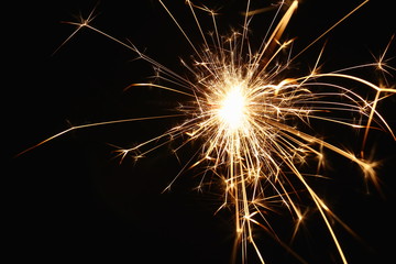 Christmas and New Year's illumination. Burning sparklers scatter bright exploding strips of sparks on a dark background.