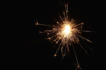 Fototapeta premium Christmas and New Year's illumination. Burning sparklers scatter bright exploding strips of sparks on a dark background.