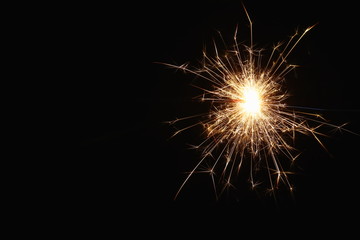 Christmas and New Year's illumination. Burning sparklers scatter bright exploding strips of sparks on a dark background.