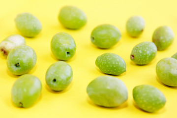 natural green fresh olives on a yellow background