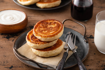Homemade pancakes stack with milk and jam on wooden background.