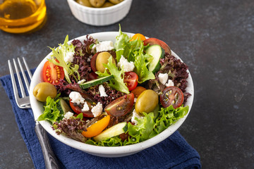 Salad of cucumbers, tomatoes, olives and fresh herbs with olive oil and pepper.