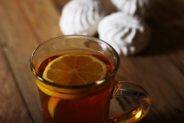 top view of a glass of tea with a slice of lemon and a white marshmallow on the table