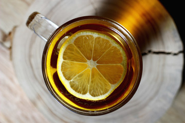 top view of a glass of tea with a slice of lemon and a white marshmallow on the table