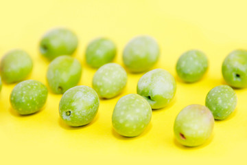 natural green fresh olives on a yellow background