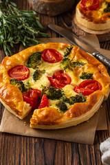 Vegetable pie with broccoli, peas, thyme. tomatoes and cheese on wooden background. Copy space.