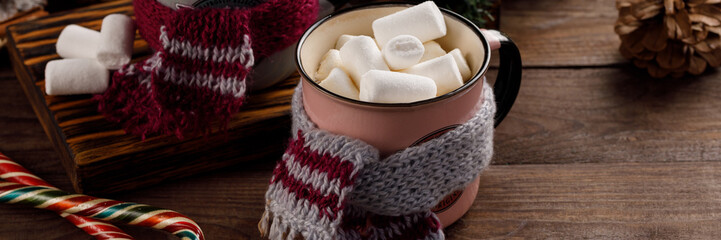 Christmas marshmallows and New Year decorations and sweet canes on a wooden background. Winter holidays, new year mood. Copy space. Close up. Banner.