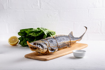 Large smoked sturgeon fish with head on white background.