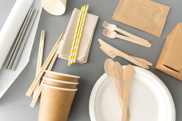 recycling, tableware and eco friendly concept - disposable dishes of paper and wood on grey background