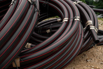 Black rubber or plastic pipes with a red lines as a construction material and equipment at building...