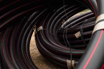 Black rubber or plastic pipes with a red lines as a construction material and equipment at building...