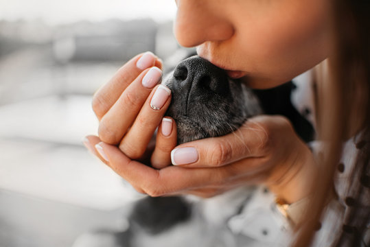 young woman kissing dog nose close up