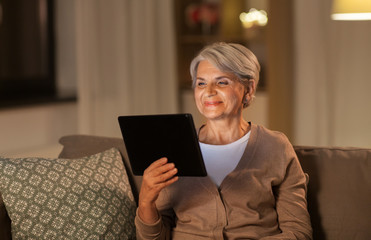 technology, old age and people concept - happy senior woman with tablet pc computer at home in...