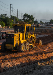 Grader is working on road construction. Grader industrial machine on construction of new roads. Heavy duty machinery working on highway. Construction equipment. Compaction of the road.