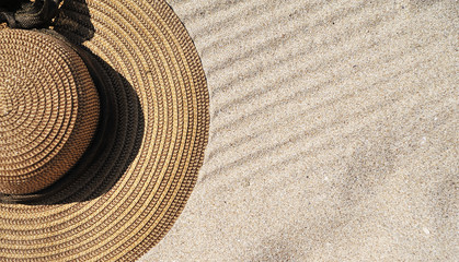 Fototapeta na wymiar Hat, sunglasses and sun protection cream on sand background.