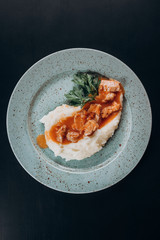 potatoes with chicken and parsley in a plate on a wooden stand