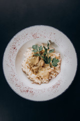 risotto with herbs in a white plate on a wooden stand