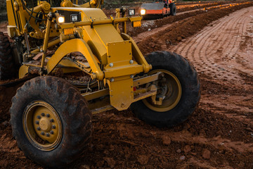Grader is working on road construction. Grader industrial machine on construction of new roads. Heavy duty machinery working on highway. Construction equipment. Compaction of the road.