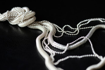 Stylish metal necklace on a black leather surface close-up. Fashion and elegance concept