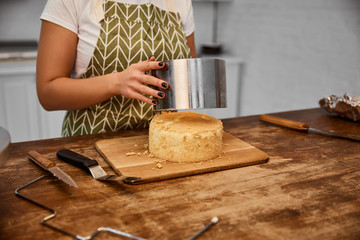 Partial view of confectioner putting cake mold on cake in kitchen