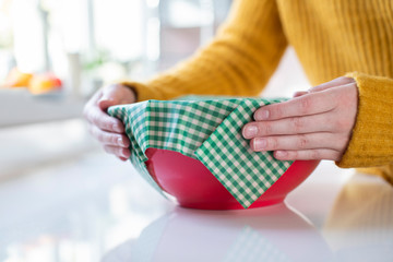 Close Up Of Woman Wrapping Food Bowl In Reusable Environmentally Friendly Beeswax Wrap - obrazy, fototapety, plakaty