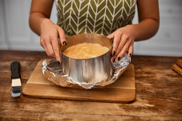 Cropped view of confectioner standing near baked cake