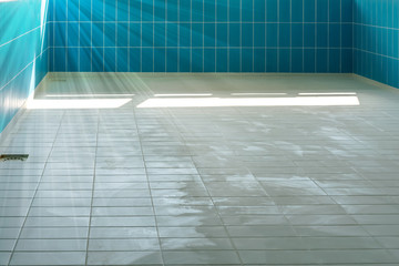 ray of sun lit dirty floor of swimming pool with blue tile