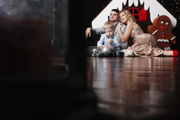 Happy family of mother, father and little son sitting on the floor and embracing