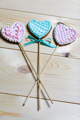 Spicy gingerbread cookie on a stick. Garnished with multicolored sugar glaze. Lies on pine boards.