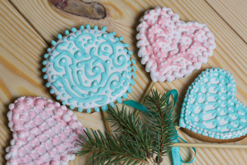 Spicy gingerbread cookie on a stick. Garnished with multicolored sugar glaze. Lies on pine boards. Near a branch of spruce.