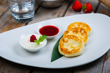 Traditional breakfast with coffee and cheesecakes, cottage cheese pancakes on a plate with syrup and jam.