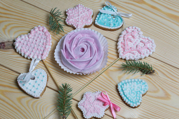Homemade marshmallows in the shape of a rose. Spicy gingerbread cookies are laid out nearby. On pine boards. View from above.
