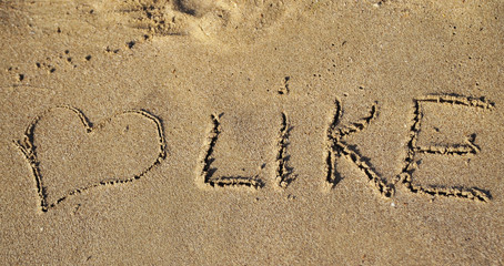 The word Like written on sand.