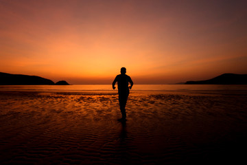 Fototapeta premium Silhouette action of a young man fun under twilight sunset sky at sea beach.