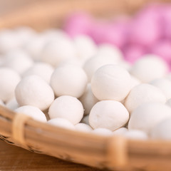 An Asia woman is making Tang yuan, yuan xiao, Chinese traditional food rice dumplings in red and white for lunar new year, winter festival, close up.