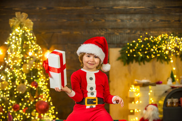 Happy cute child in Santa hat with present have a Christmas. Christmas kids. Christmas decorations. Little Santa Claus gifting gift.