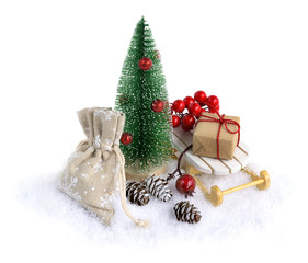 Fototapeta na wymiar Miniature Christmas tree in snow with Christmas gifts on the sleigh isolated on white.