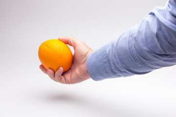 Naranja entera en la manode una persona adulta; naranja madura y preparada para ser consumida.