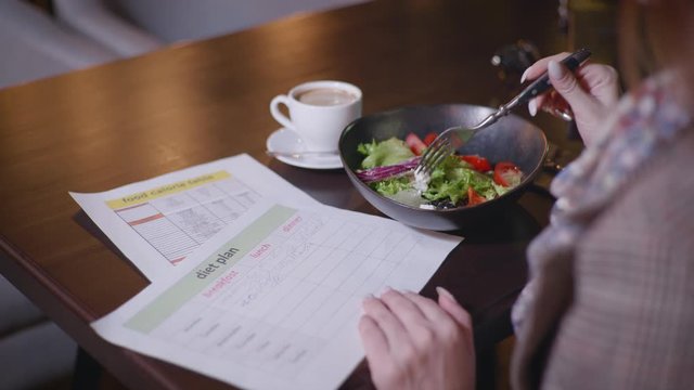 Diet Plan, Timely Young Beautiful Girl Monitors Her Diet And Counts Calorie Content Sitting At A Table In A Cafe, Concept Of Healthy Eating