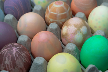 various dyed easter eggs in an egg carton