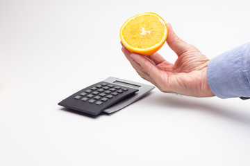 Naranja en la mano adulta de una persona; media naranja ya preparada para ser exprimida y hacer un...