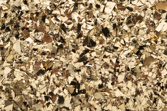 Gold foil confetti on white background. Festive, party or holiday glitter backdrop. Flat-lay, close-up.