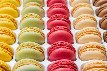 Classical french dessert. Colorful macarons in bright pink green yellow cream chocolate stacked in a box, selective focus