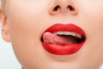 Obraz premium cropped view of woman with red lipstick licking lips isolated on white