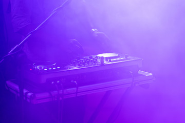 club dj plays music on stage in nightclub.Hand of disc jockey adjusting sound track volume level.Professional audio equipment on music festival