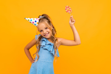 joyful birthday girl with candy on a yellow background with copy space