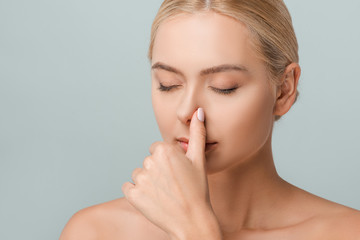 attractive naked woman touching nose isolated on grey